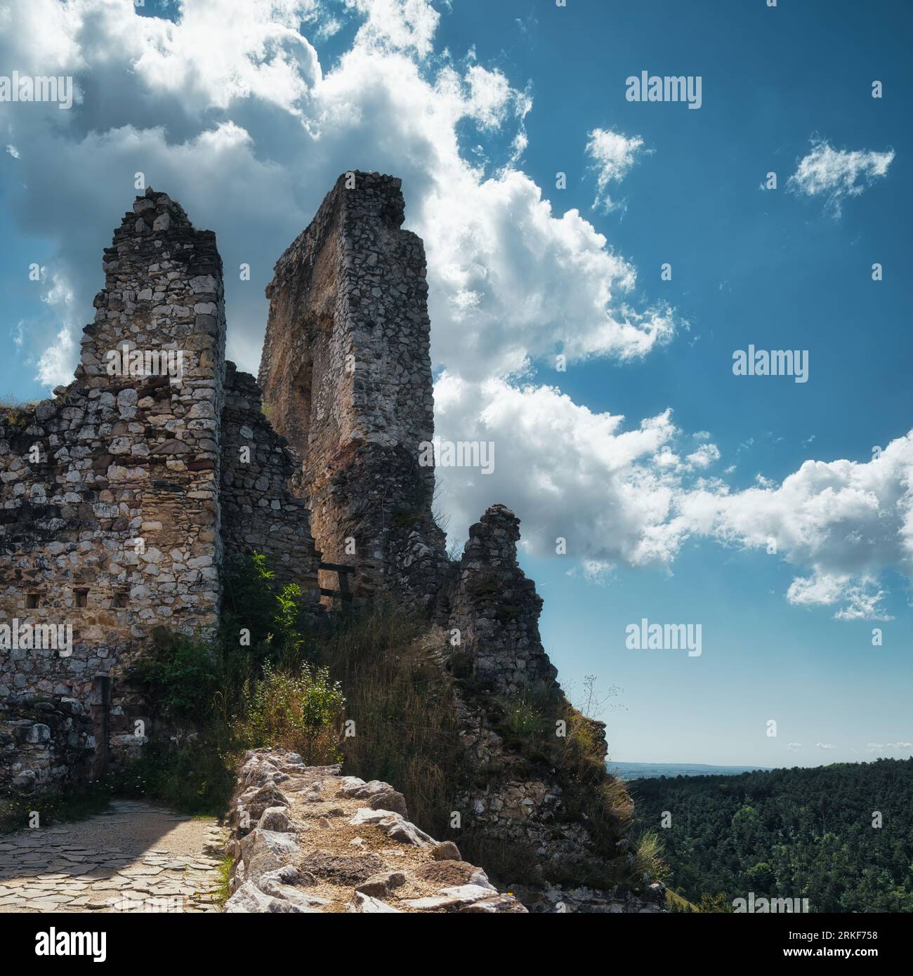 Rovine medievali in pietra del castello di Cachtice che si innalzano sopra la campagna boschiva sotto un suggestivo cielo blu in Slovacchia. Foto Stock