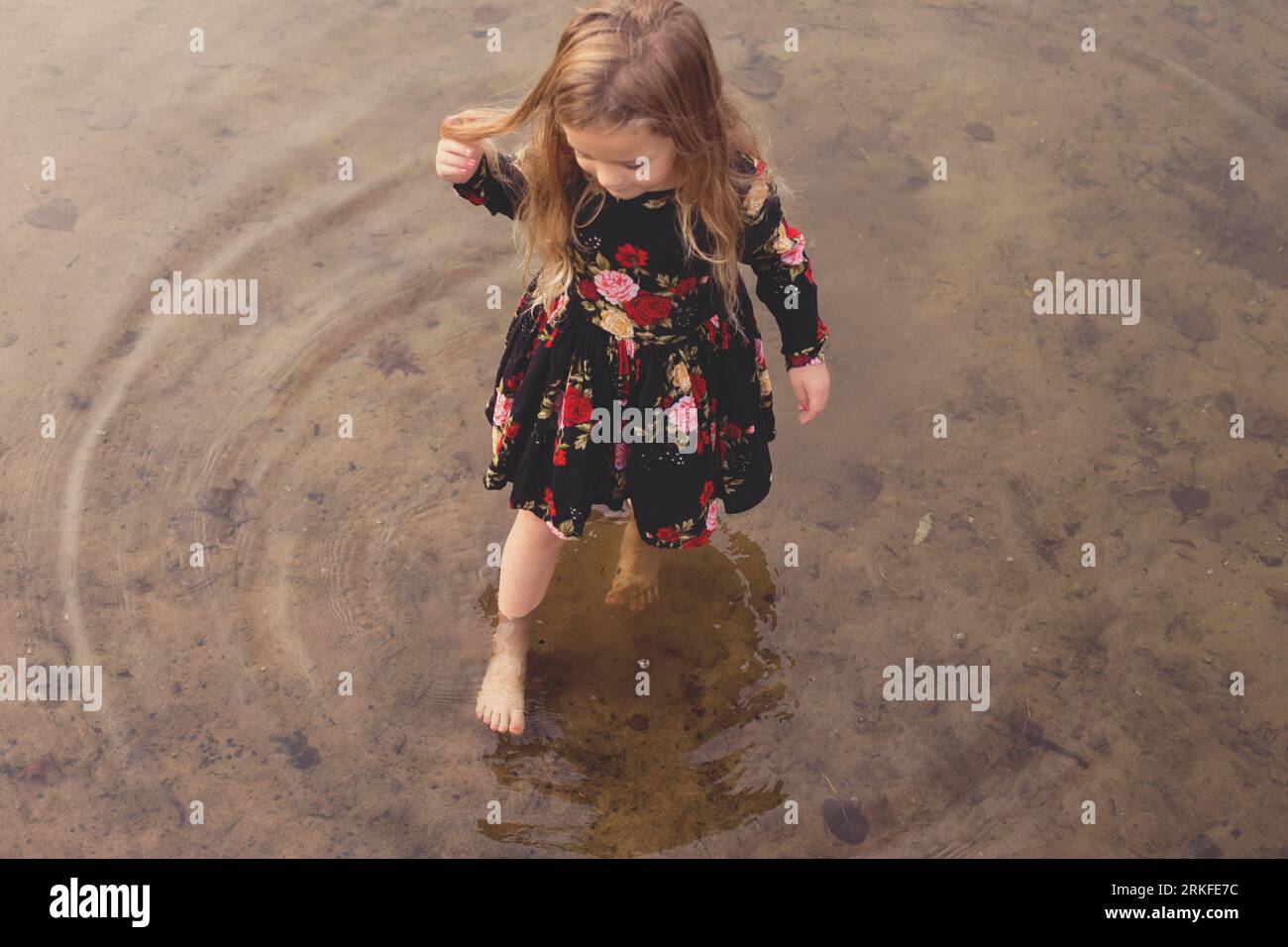 Un bambino coraggioso esplora felicemente le acque basse di un lago Foto Stock