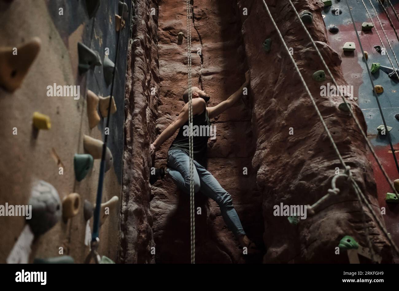 Uomo forte che fa arrampicata su una parete interna Foto Stock