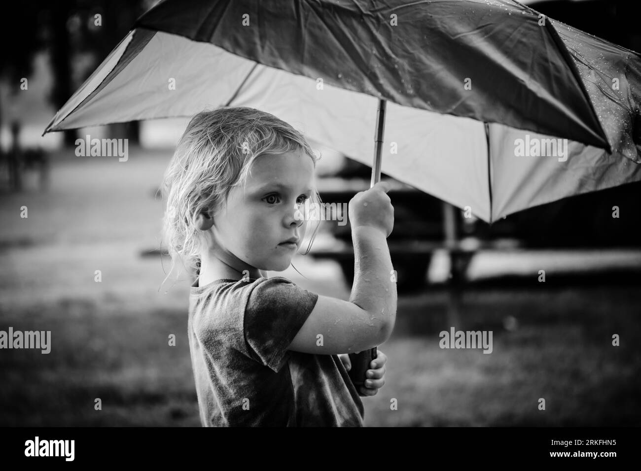 Bambino sotto un ombrello sotto la pioggia Foto Stock