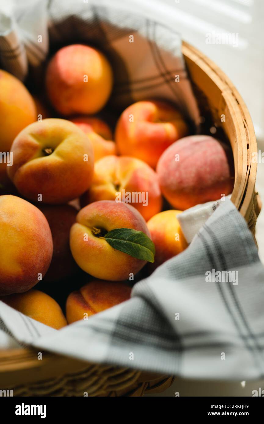 Chiudere il cestello con le pesche fresche alla luce del sole avvolte in un asciugamano Foto Stock