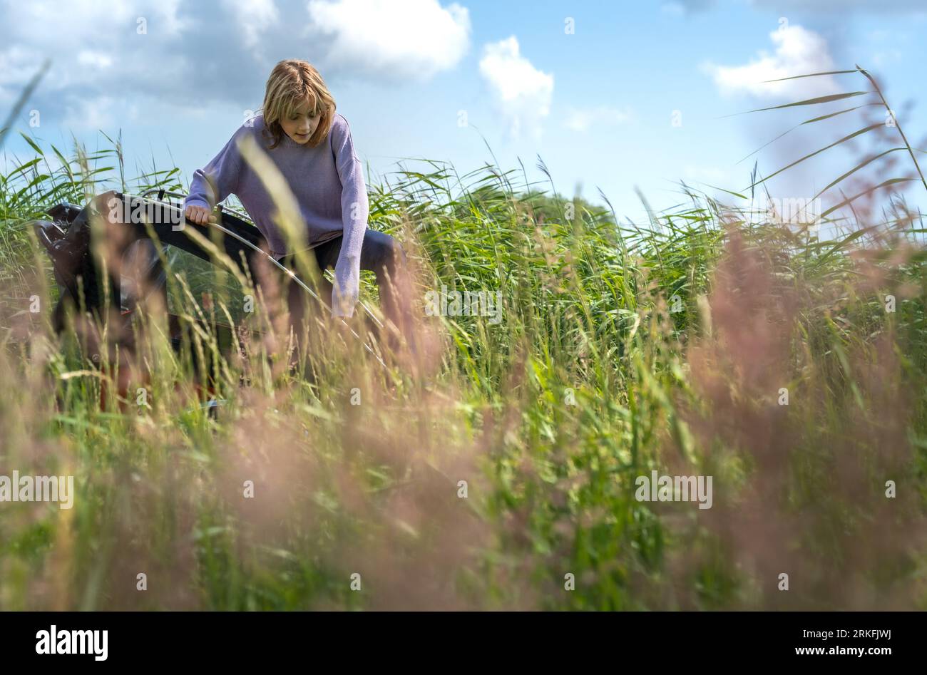 Young Girl che si arrampica su Cargo Bike in un campo in Danimarca Foto Stock