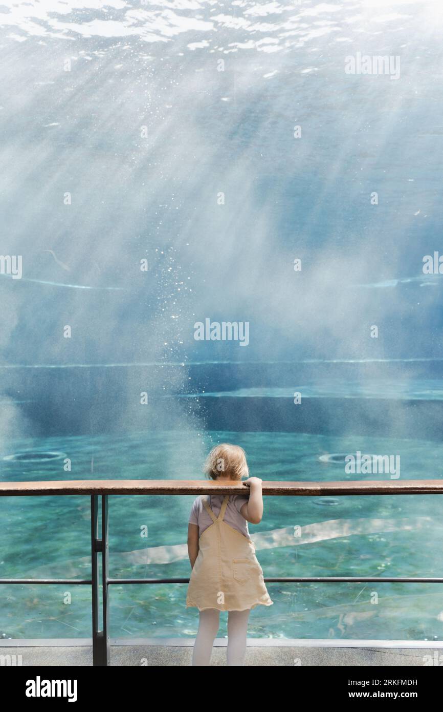 Bambina sola in un acquario vuoto, acquario a Genova, Italia Foto Stock