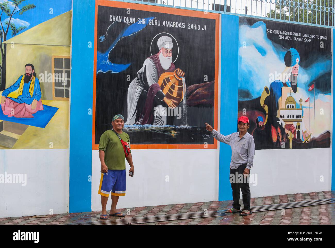 Gli artisti filippini Noel Buenacifra Jr e Sr di fronte al dipinto ad affresco hanno dipinto per il tempio indiano Sikh Sat Kartar, San Pablo Laguna, Filippine Foto Stock