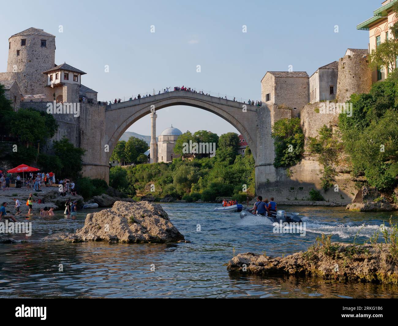 Spiaggia accanto al fiume Neretva e turisti a Stari Most (Ponte Vecchio) e alla Moschea Koski-Mehmed Pasha. Mostar, Bosnia ed Erzegovina, 20 agosto 2023. Foto Stock
