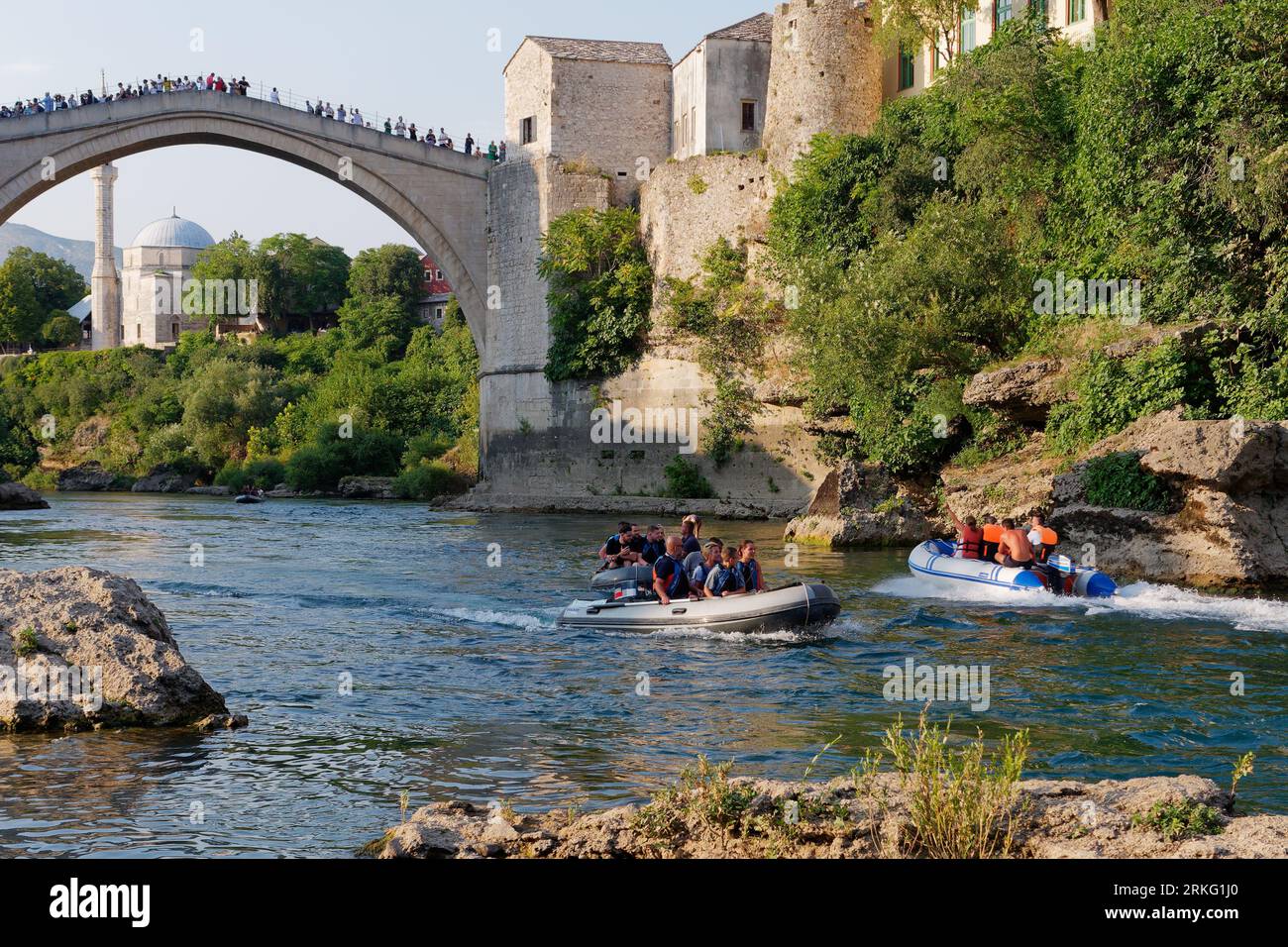 Motoscafi sul fiume Neretva e Stari Most (Ponte Vecchio) con la Moschea Koski-Mehmed Pasha alle spalle a Mostar, Bosnia ed Erzegovina, 20 agosto 2023. Foto Stock