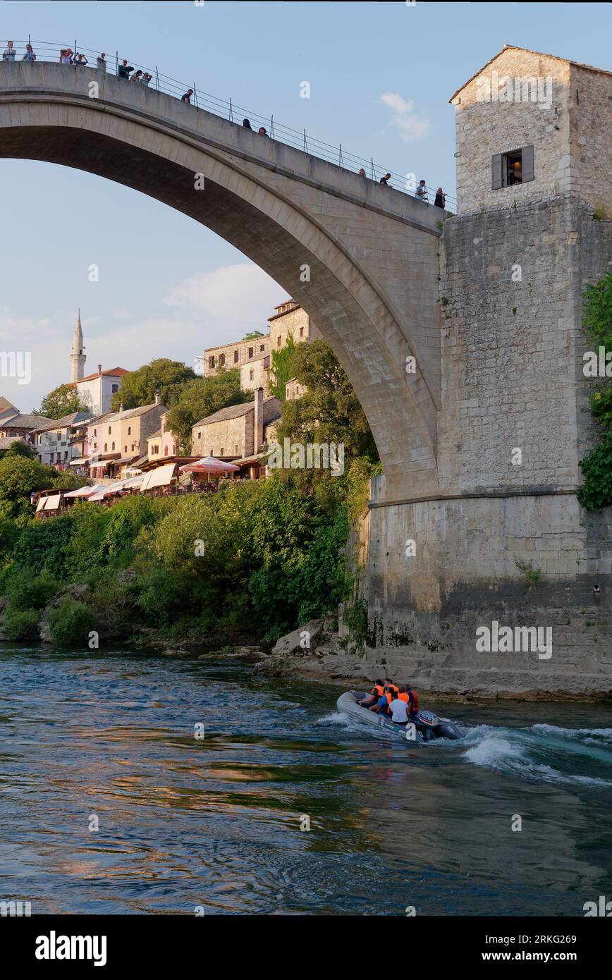 Motoscafo/gommone sul fiume Neretva mentre la gente visita lo Stari Most (Ponte Vecchio) nella città di Mostar, Bosnia ed Erzegovina, 20 agosto 2023. Foto Stock