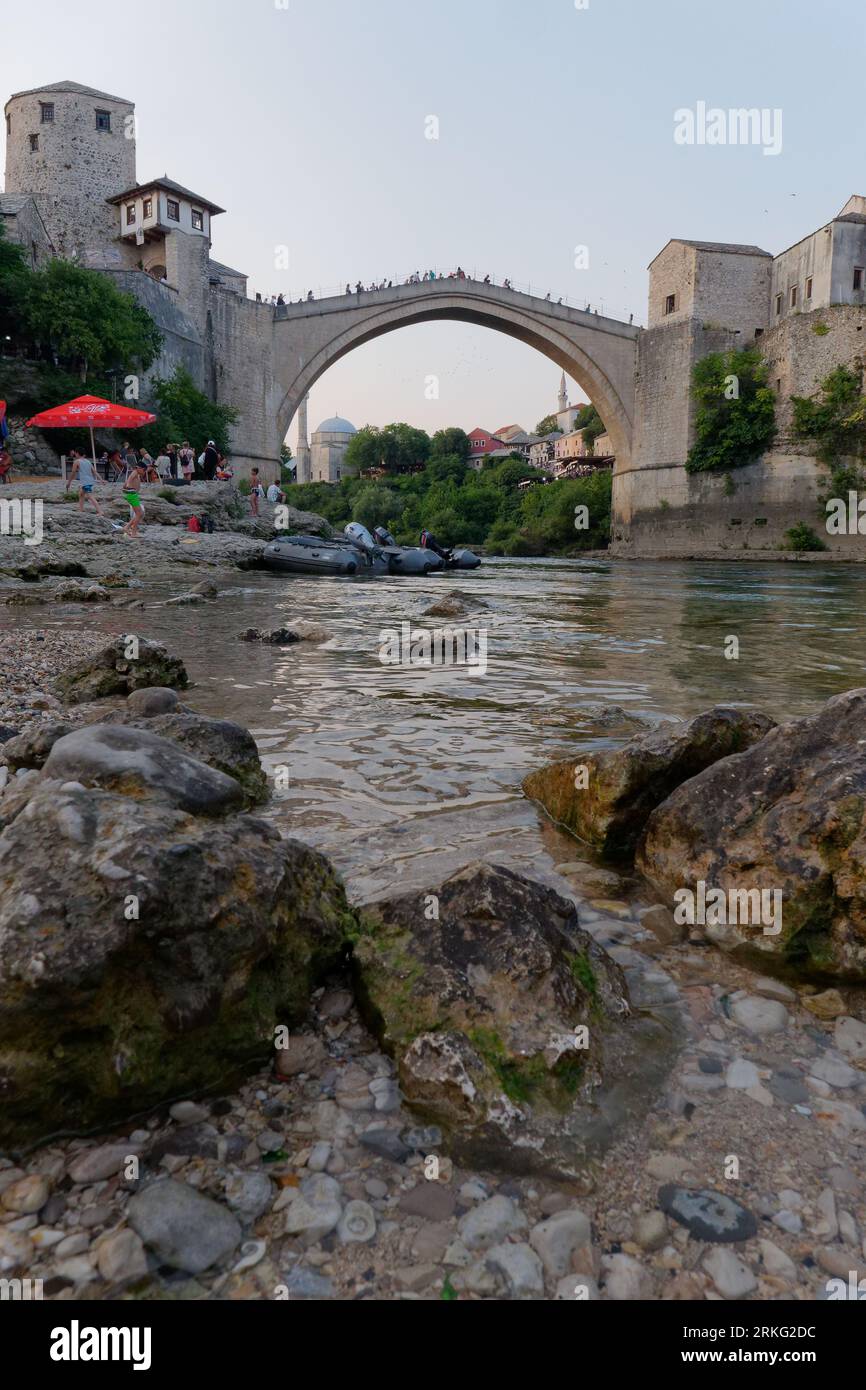 La spiaggia rocciosa del fiume Neretva e Stari Most (Ponte Vecchio) nella città di Mostar, Bosnia ed Erzegovina, 20 agosto 2023. Foto Stock