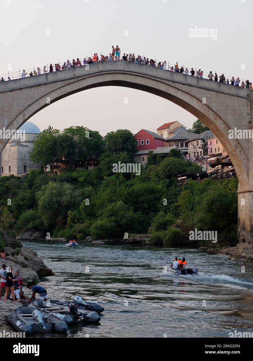 Motoscafo/gommone sul fiume Neretva mentre la gente visita lo Stari Most (Ponte Vecchio) nella città di Mostar, Bosnia ed Erzegovina, 20 agosto 2023. Foto Stock