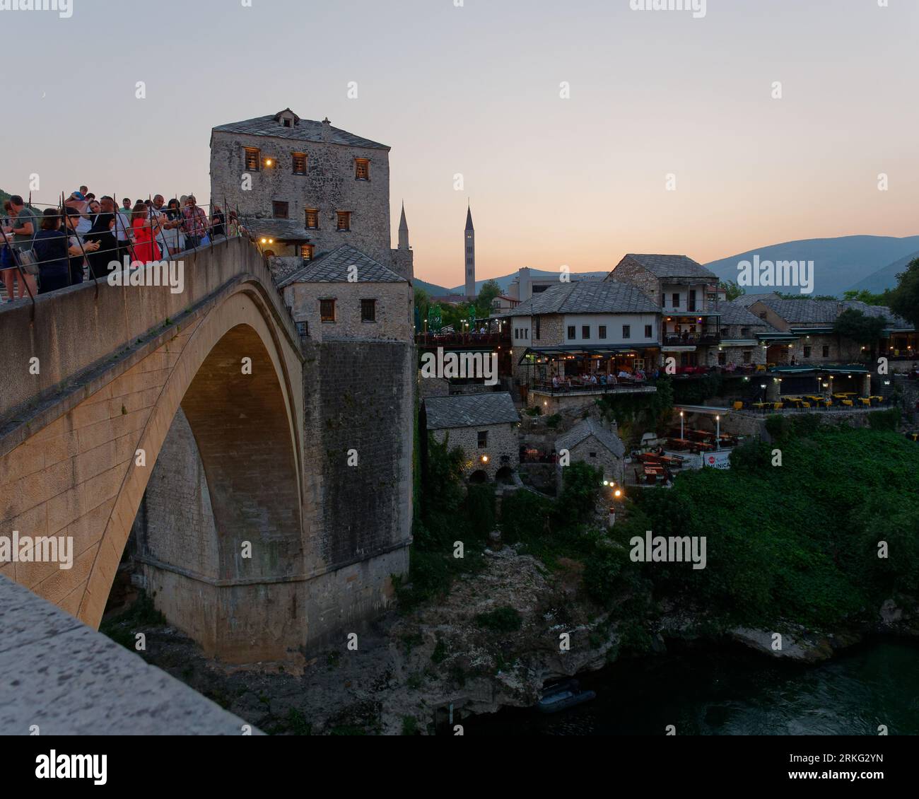 I turisti apprezzano la vista dallo Stari Most (Ponte Vecchio) sul fiume Neretva in una serata estiva a Mostar, Bosnia ed Erzegovina, 20 agosto 2023. Foto Stock