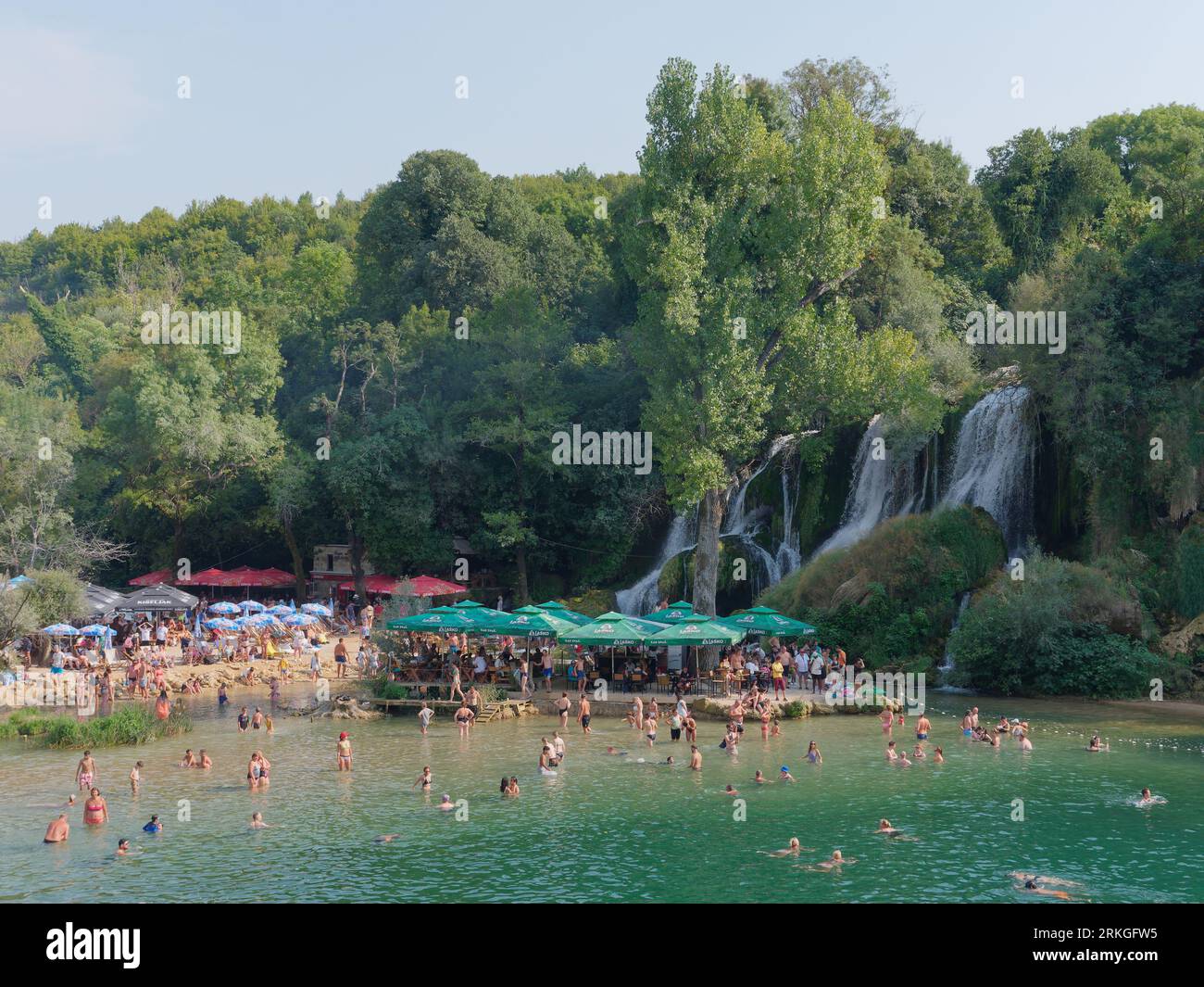 In estate, le persone apprezzano l'area della spiaggia sulla cascata Kravica sul fiume Trebižat, in una zona carsica della Bosnia ed Erzegovina. 24 agosto 2023 Foto Stock