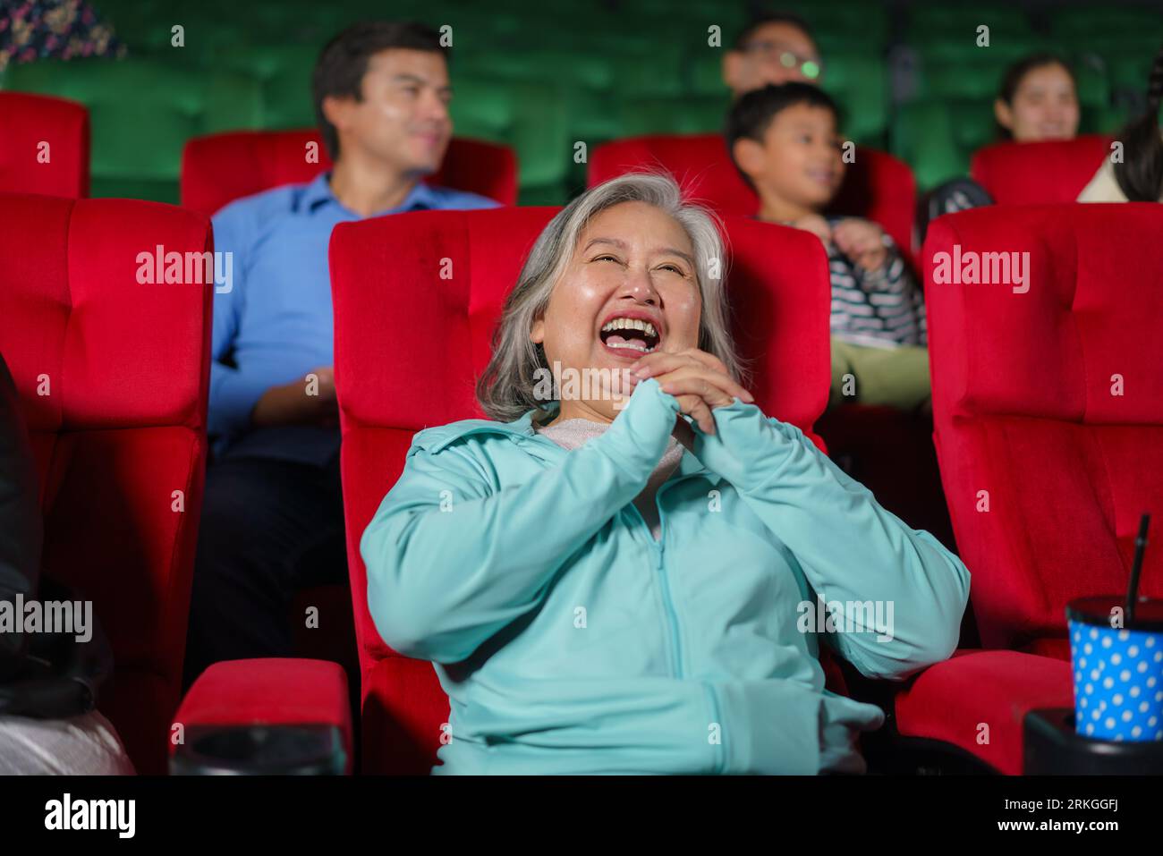 Le donne anziane asiatiche sono felici di guardare film al cinema, tenendo in mano popcorn. Foto Stock