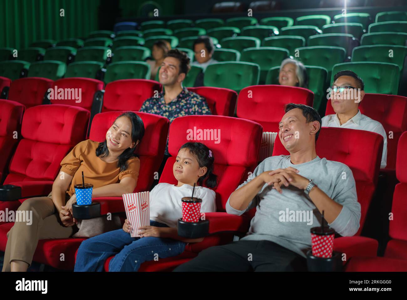 La felice famiglia asiatica di padre, madre, figlia e nonna apprezza i momenti del weekend al cinema, condividendo la gioia e la compagnia mentre guardi un film Foto Stock