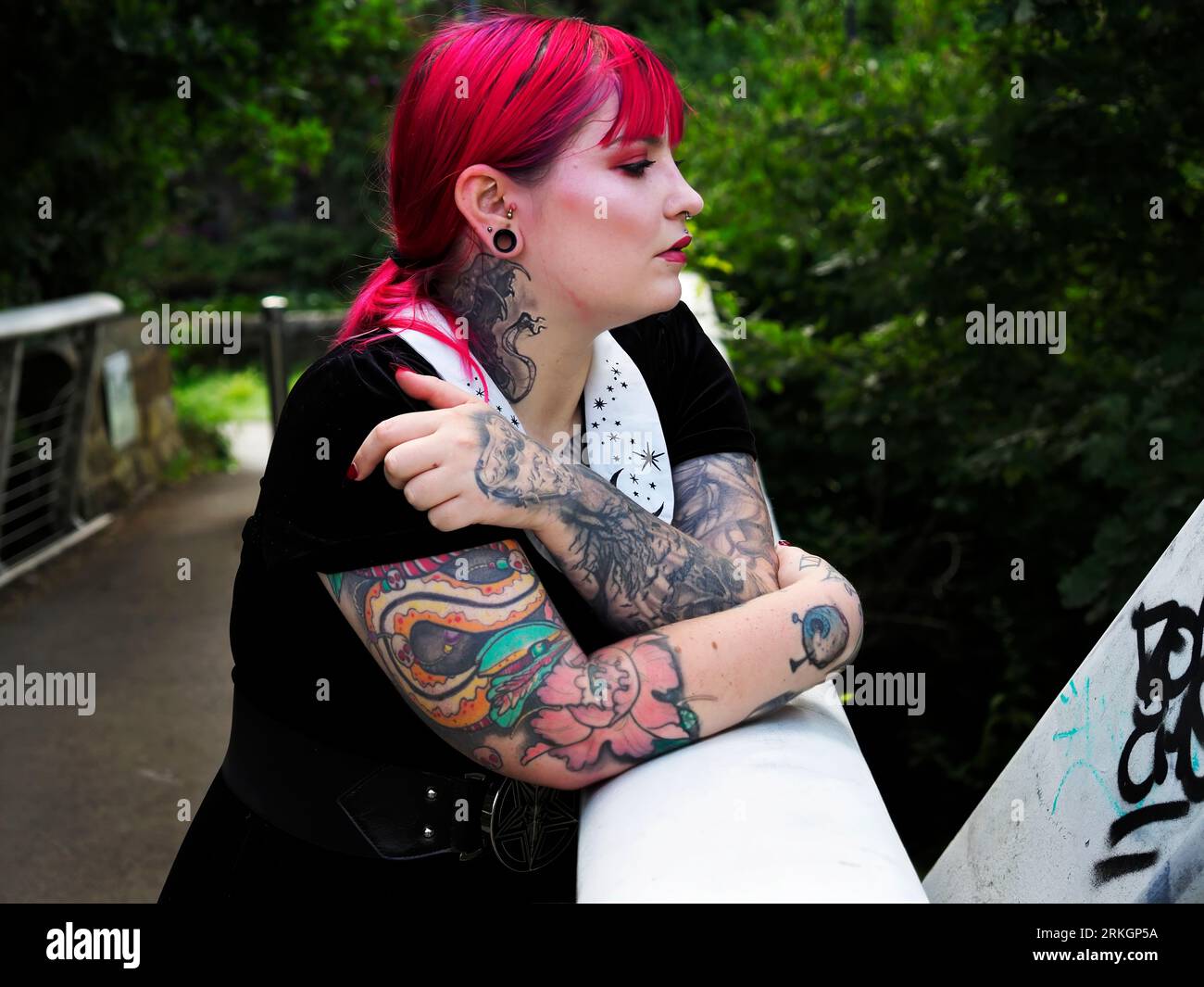 Donna di vent'anni con capelli rossi tinti e tatuaggi appoggiati su una passerella metallica a Leeds, West Yorkshire, Inghilterra Foto Stock
