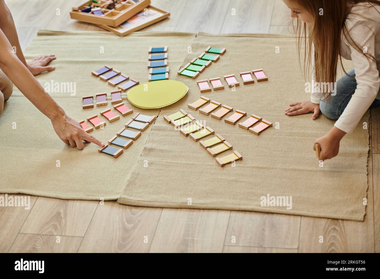 materiale montessori, ragazza e insegnante vicino al colore gioco educativo in forma di sole, educazione precoce Foto Stock
