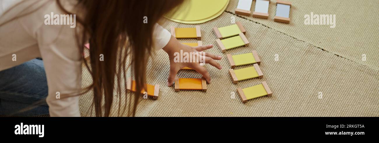 materiale montessori, ragazza che gioca a un gioco educativo a colori in forma di sole, educazione precoce, banner Foto Stock