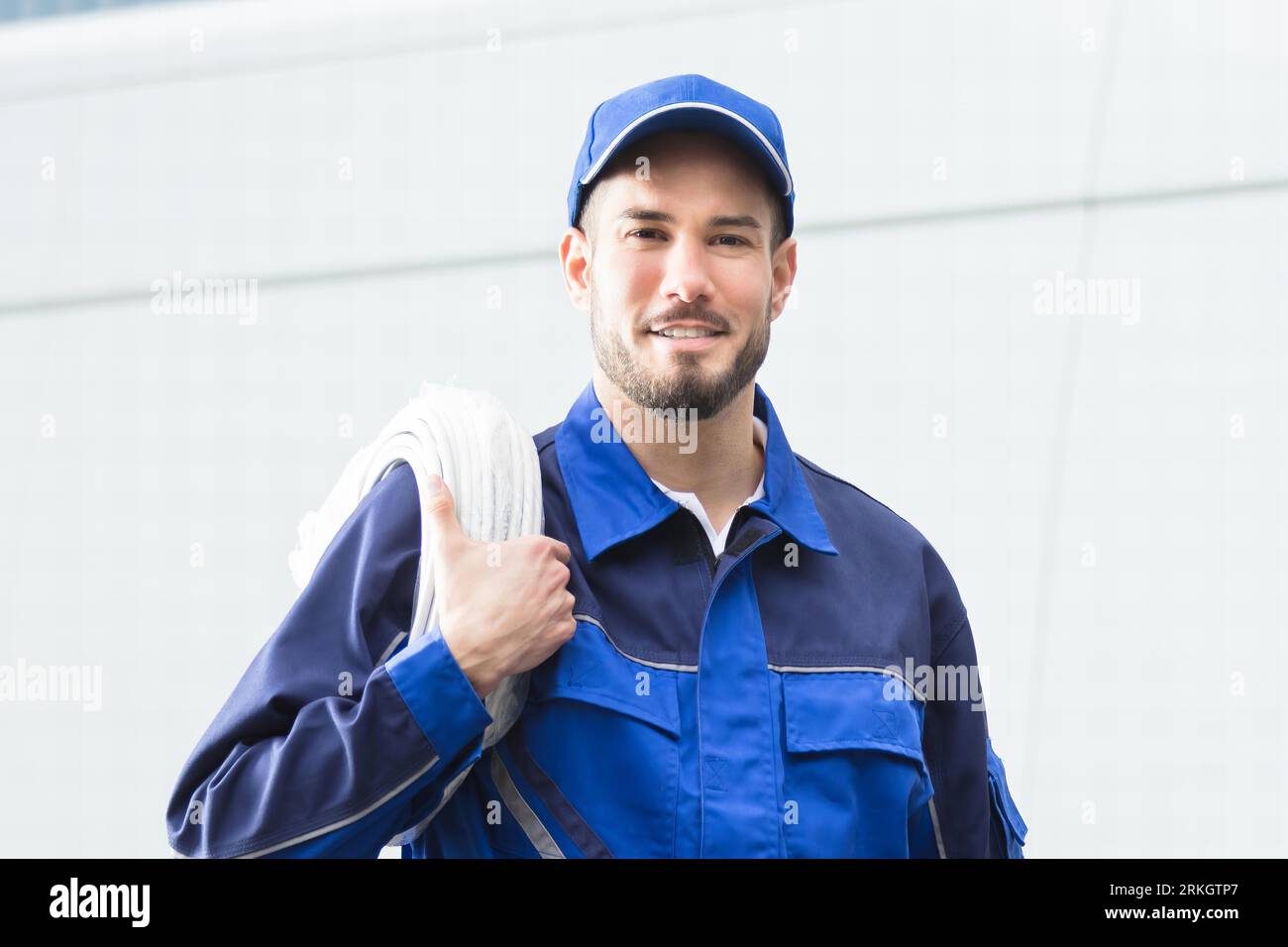 Sorridente aggiustatore con Toolbox e cavo in piedi nella parte anteriore del veicolo Foto Stock