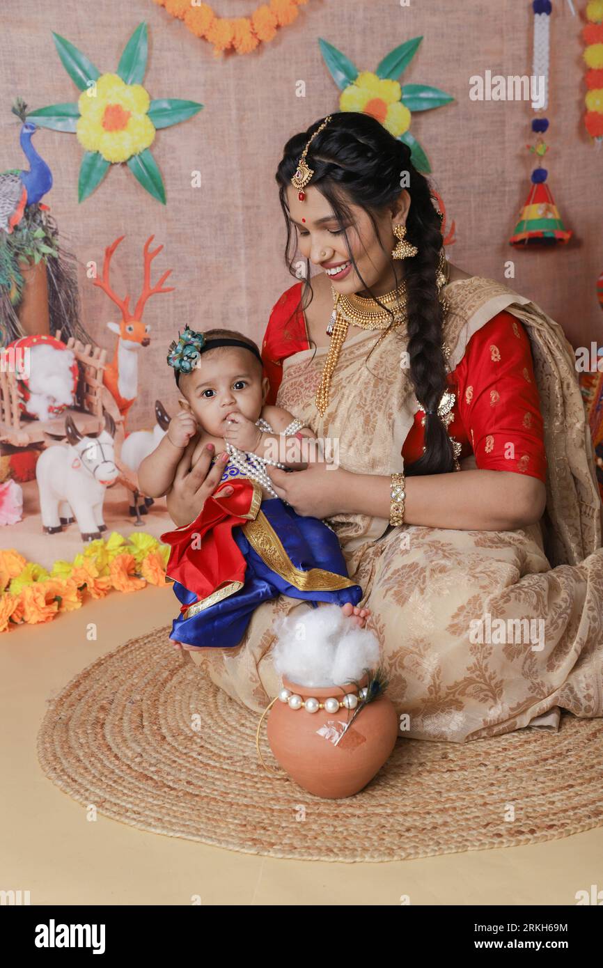 Concetto di Janmashtami. Madre seduta con il suo bambino carino vestito da piccola krishna. Foto Stock
