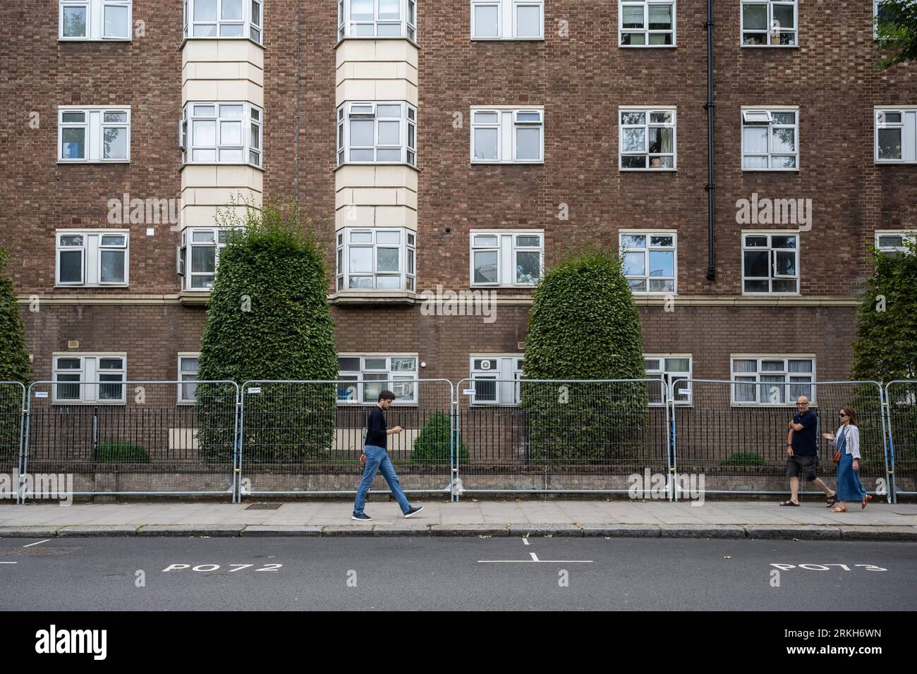 Londra, Regno Unito. 25 agosto 2023. La gente passa attraverso le proprietà protette dietro le ringhiere prima del Carnevale di Notting Hill, poiché si prevede che il più grande festival di strada d’Europa, che celebra la cultura caraibica, accoglierà oltre 1 milione di persone ogni giorno. È stato anche riferito che Kensington e Chelsea Council hanno finanziato un fine settimana di vacanza per 41 adulti anziani e vulnerabili che vivono sulla strada del Carnevale che potrebbero lottare per lasciare le loro proprietà durante i festeggiamenti credito: Stephen Chung / Alamy Live News Foto Stock