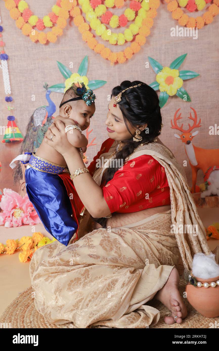 Concetto di Janmashtami. Madre seduta con il suo bambino carino vestito da piccola krishna. Foto Stock