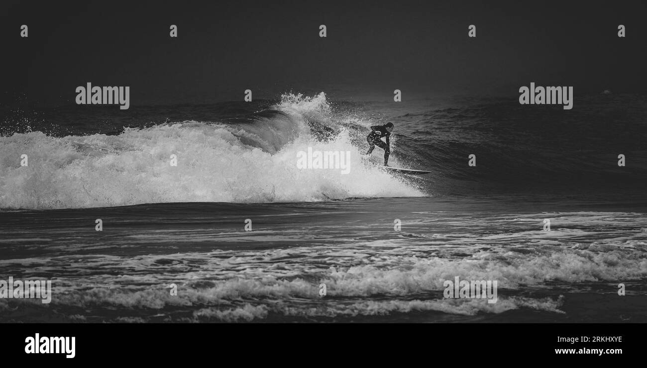 Una persona che cavalca una tavola da surf su un'onda sopra la superficie dell'oceano, godendosi l'acqua salata e il sole Foto Stock