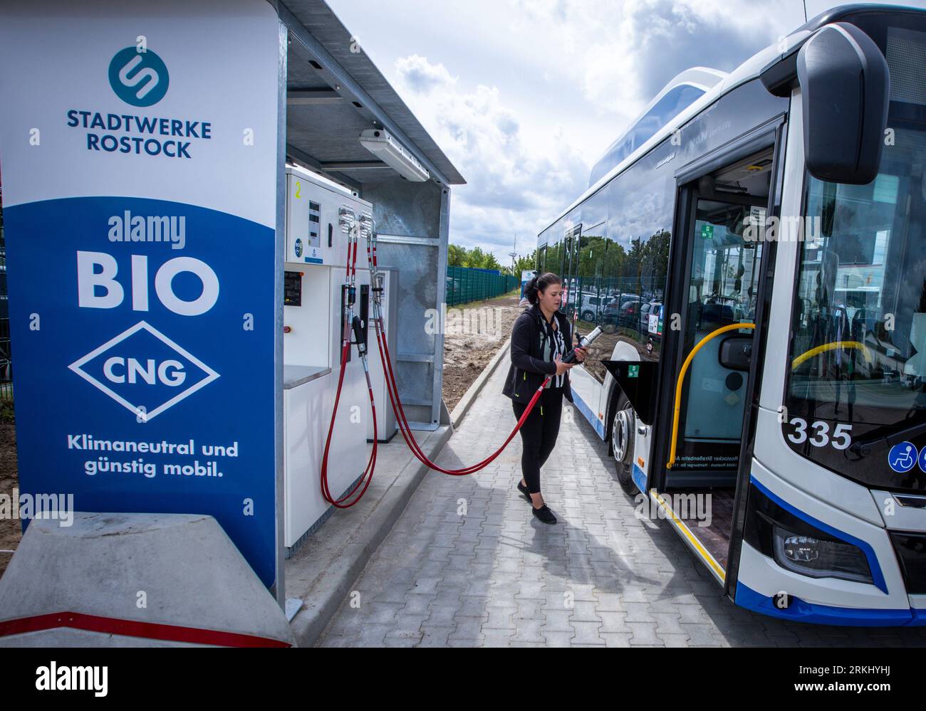 Rostock, Germania. 2 agosto 2023. Susann Klier inserisce il tubo flessibile del serbatoio per il rifornimento di biometano nell'albero del serbatoio di un bus di servizio presso il nuovo deposito di Rostocker Straßenbahn AG (RSAG). Dopo sei mesi di lavori di conversione, il sito per gli autobus di servizio regolare è stato adattato per sistemi di trasmissione alternativi. Gli autobus possono essere riforniti di energia elettrica e biometano, e il piano è quello di convertire gradualmente tutti i servizi di autobus in sistemi di guida rispettosi del clima nei prossimi anni. Credito: Jens Büttner/dpa/Alamy Live News Foto Stock