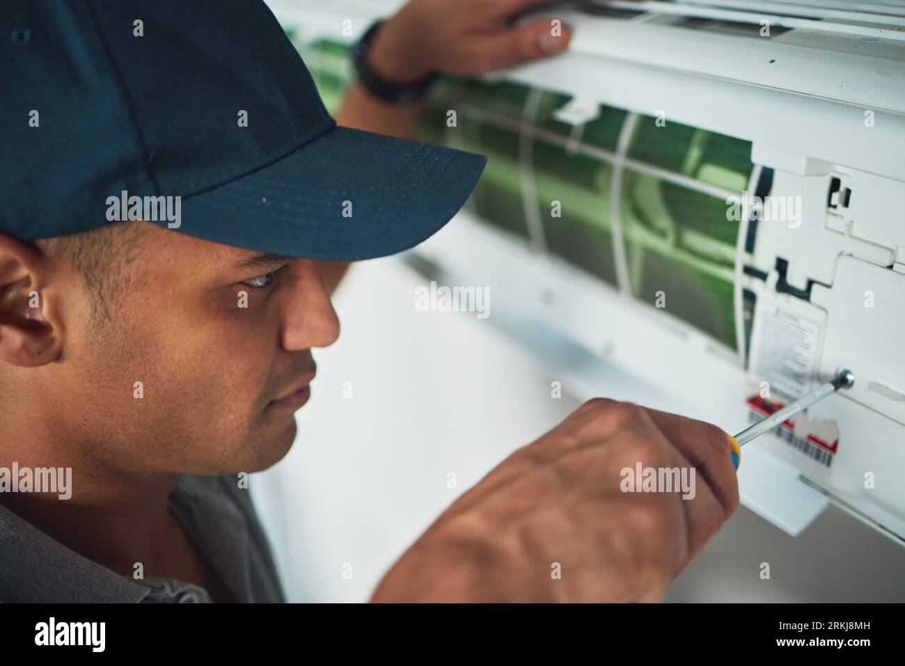 Viso, mano e uomo per la riparazione o la manutenzione dell'impianto di climatizzazione in un ufficio per la circolazione o il riscaldamento centralizzato. Costruzione, utensili o cacciavite con un Foto Stock