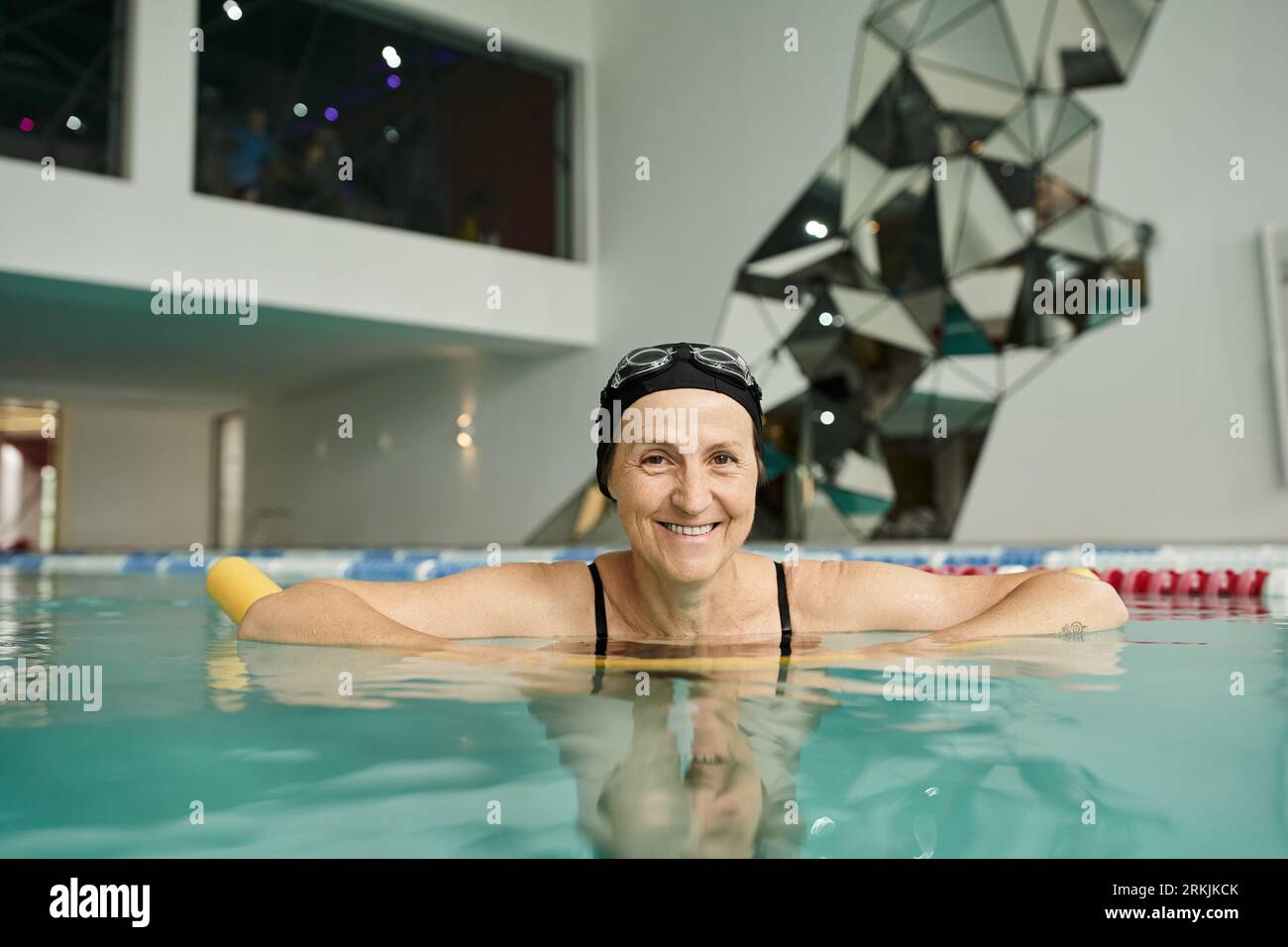 donna matura felice in cuffia e occhiali nuoto in piscina, stile di vita sano, sorriso e sport Foto Stock