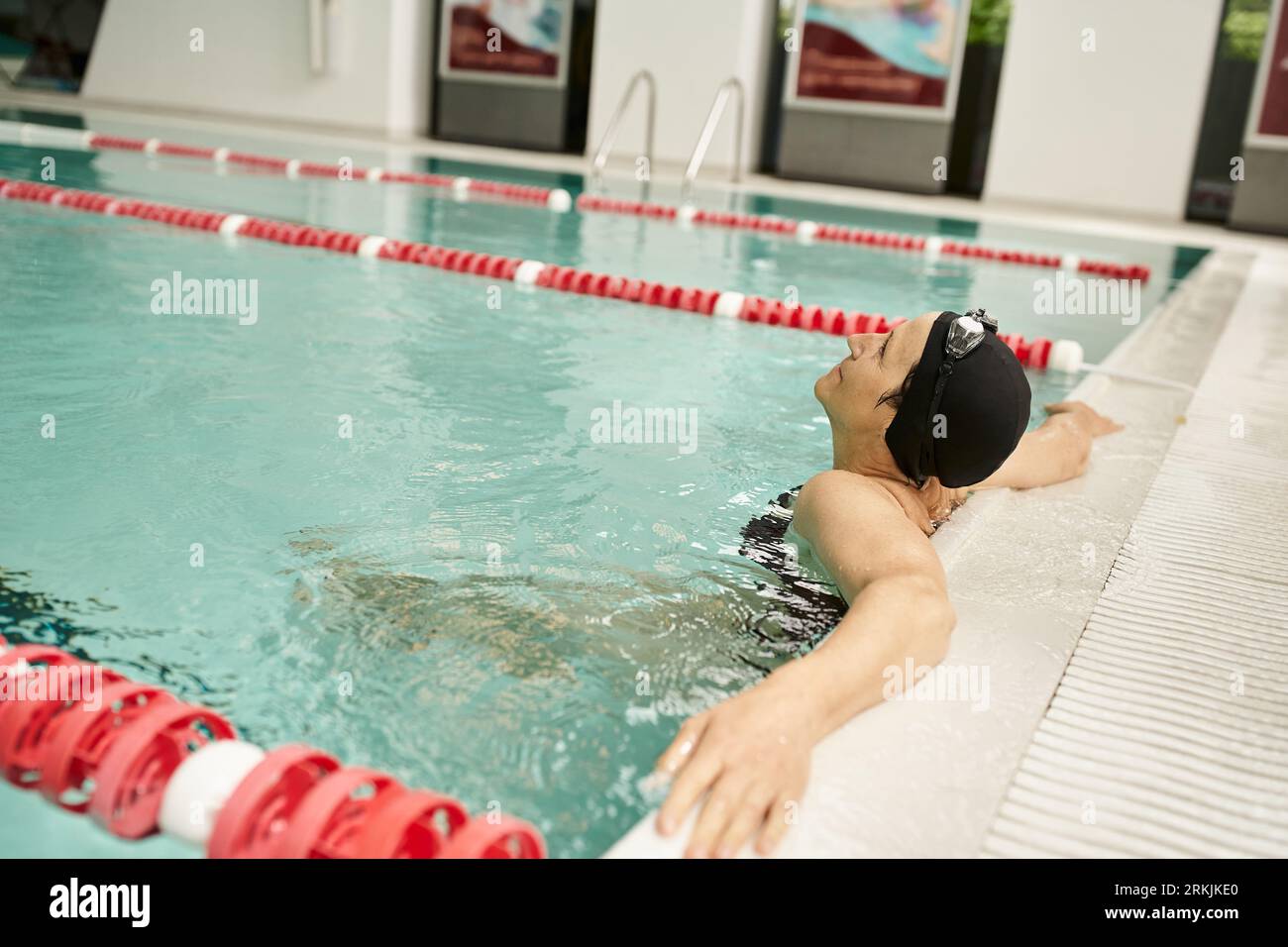 donna di mezza età che si rilassa a bordo piscina, cuffia e occhiali da bagno, sport, stile di vita sano, tranquillo Foto Stock