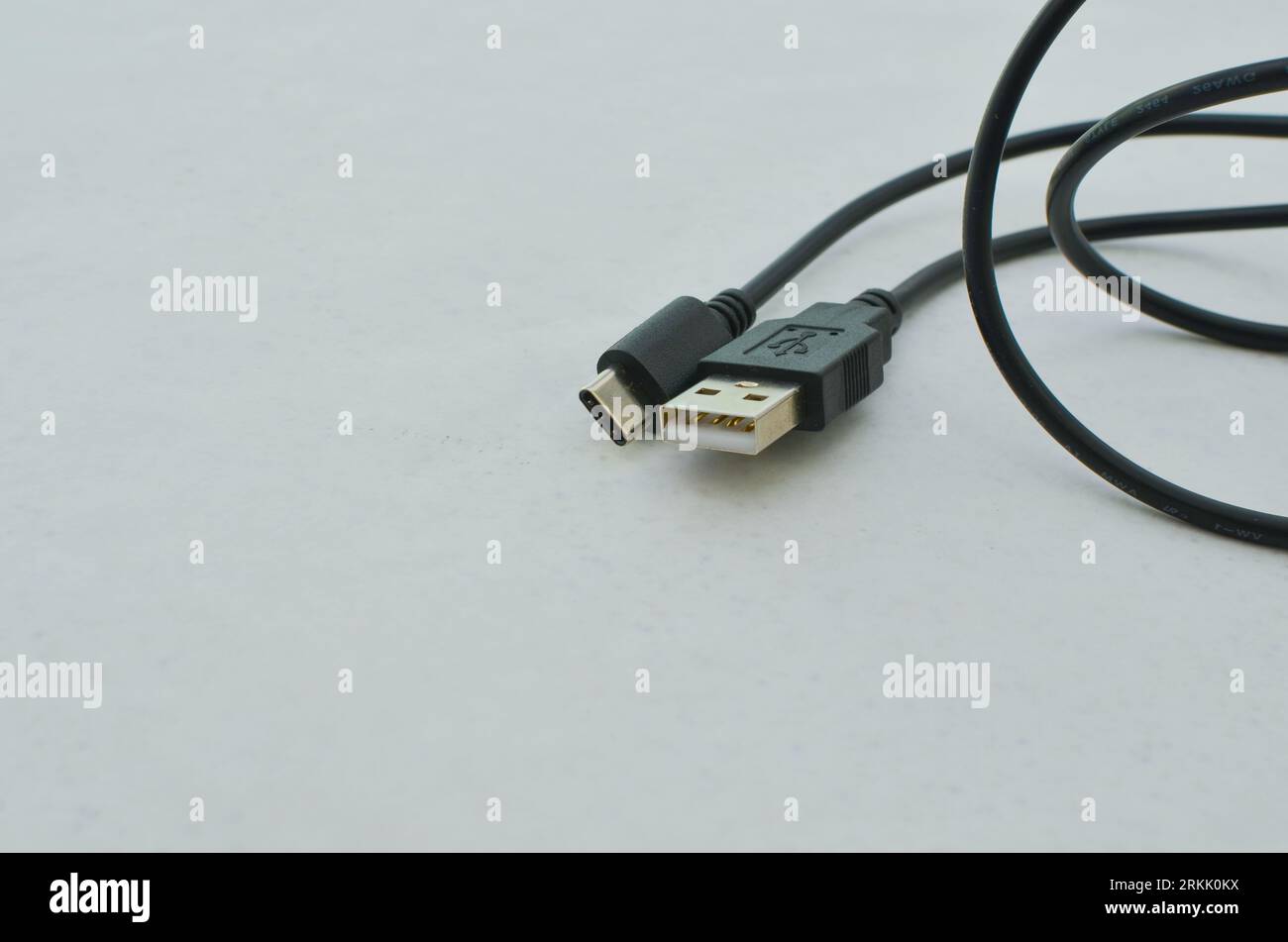 Cavo USB di tipo C nero evidenziato su una superficie trasparente, perfetto per i moderni concetti tecnologici. Cavo USB di tipo C nero per una maggiore velocità Foto Stock