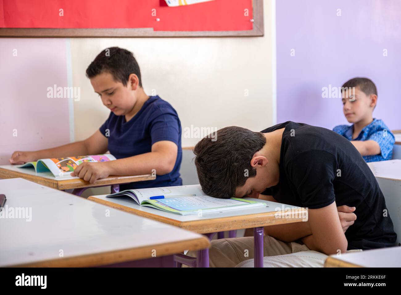 Uno studente che mette la testa sulla scrivania, sembra non sentirsi bene o non dormire Foto Stock