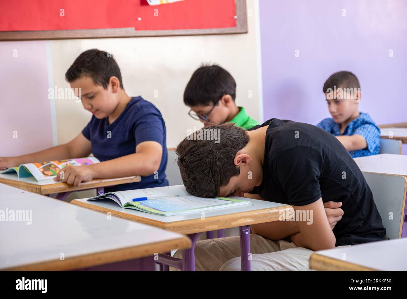 Uno studente che mette la testa sulla scrivania, sembra non sentirsi bene o non dormire Foto Stock