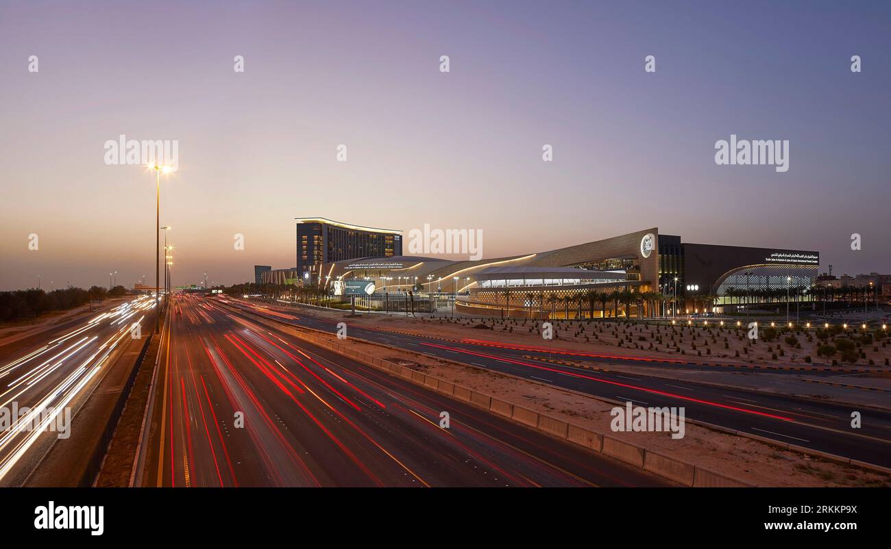 Elevazione al crepuscolo con strada e cielo al tramonto. 360 Mall, Kuweit City, Kuwait. Architetto: CRTKL, 2021. Foto Stock