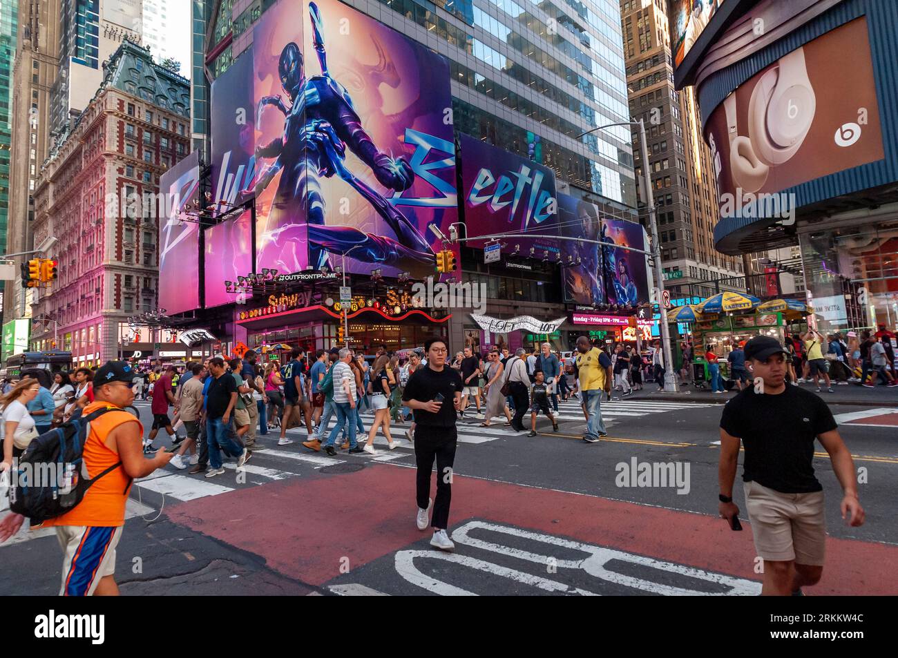 Orde di persone attraversano West 42nd Street sotto la pubblicità per la Warner Bros. Picture’ “Blue Beetle” film in Times Square a New York venerdì 18 agosto 2023. Nel suo weekend di uscita "Blue Beetle" ha soppiantato "Barbie" come il film di maggior incasso con una stima di 25,4 milioni di dollari. . (© Richard B. Levine) Foto Stock