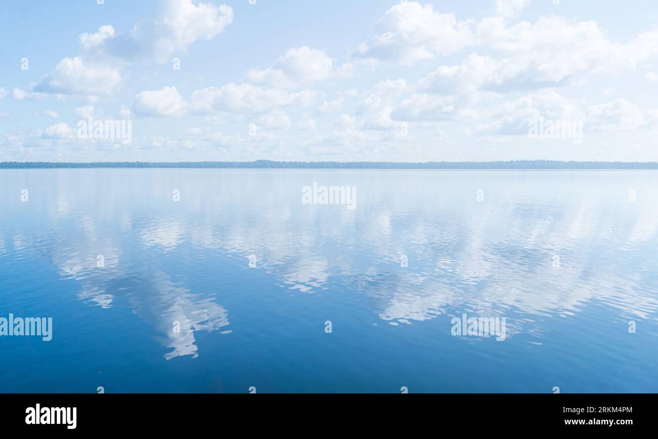 paesaggio naturale, paesaggio acquatico con un grande corpo d'acqua sotto un cielo blu con nuvole e una lontana riva boscosa Foto Stock