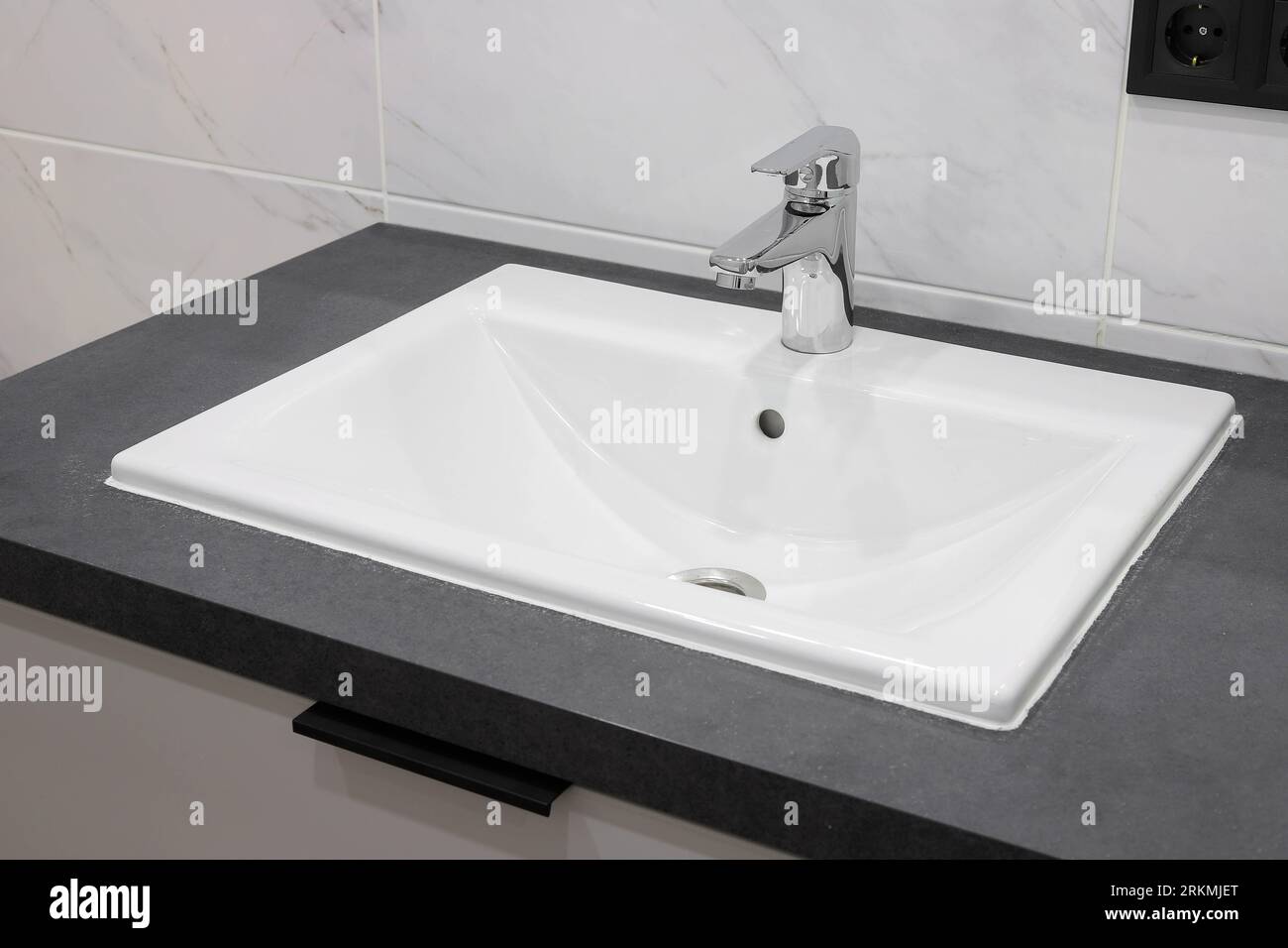 Rubinetto cromato con lavandino in ceramica bianca all'interno del bagno Foto Stock Rubinetto cromato con lavandino in ceramica bianca all'interno del bagno Foto Stock
