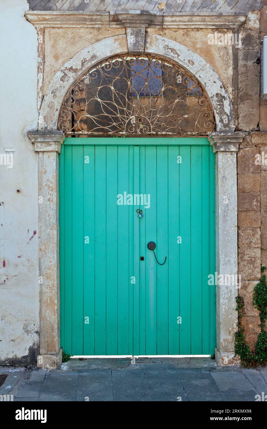 Antica porta tradizionale in legno di colore verde chiaro in una vecchia casa con arco in pietra e architrave in ferro, nella città di Preveza, regione dell'Epiro, Grecia, Europa Foto Stock