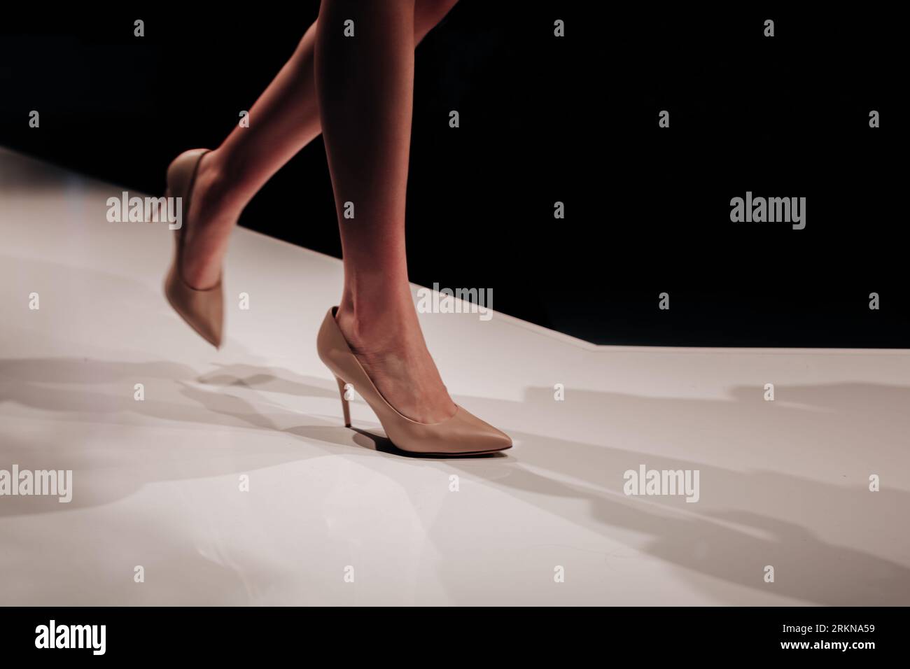 Gambe femminili con tacco alto beige che sfilano per la sfilata di moda. Elegante e minimalista Foto Stock