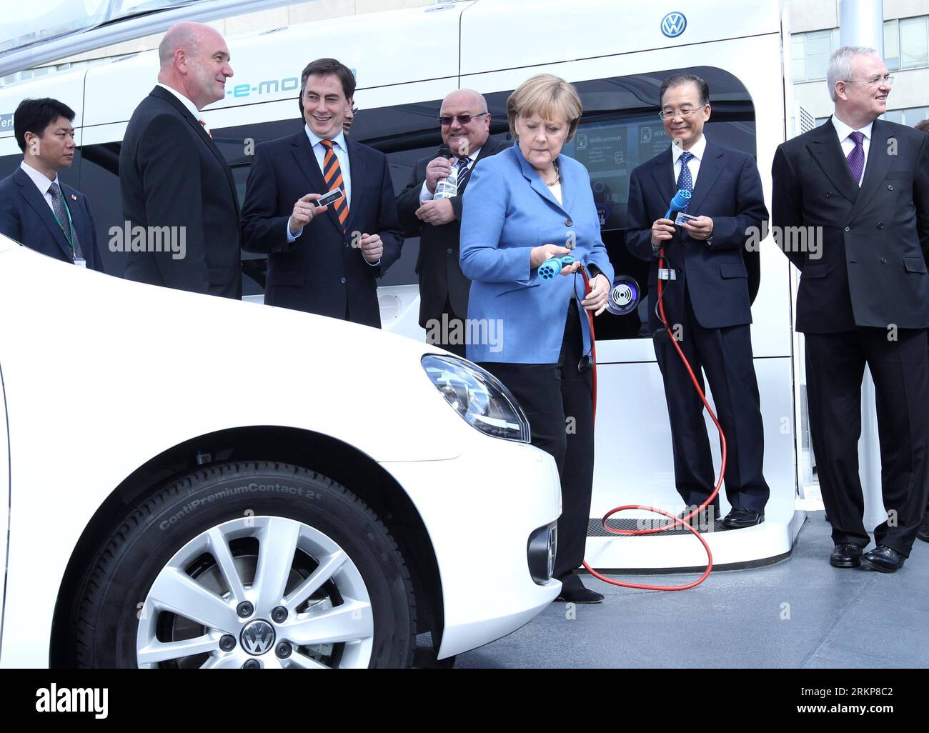 120423 -- HANNOVER, 23 aprile 2012 Xinhua -- il Premier cinese Wen Jiabao 2nd R e il cancelliere tedesco Angela Merkel 3rd R tengono i cavi di alimentazione durante una dimostrazione per la ricarica di auto elettriche, mentre visitano il quartier generale della Volkswagen a Wolfsburg, Germania, 23 aprile 2012. Xinhua/Pang Xinglei hdt GERMANY-CHINA-WEN JIABAO-VOLKSWAGEN-VISIT PUBLICATIONxNOTxINxCHN Foto Stock