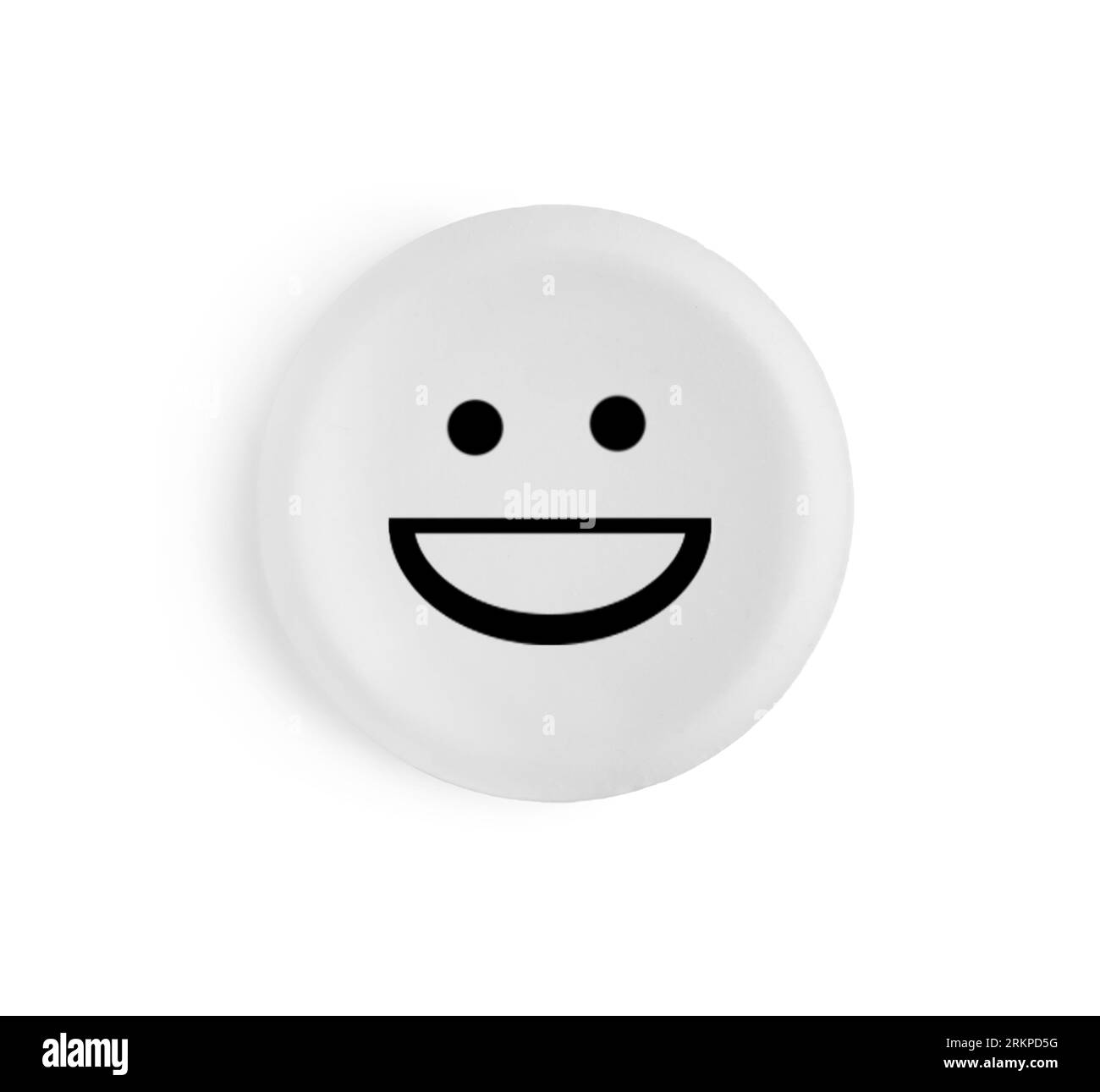 Una pillola rotonda con faccia sorridente su sfondo bianco Foto Stock