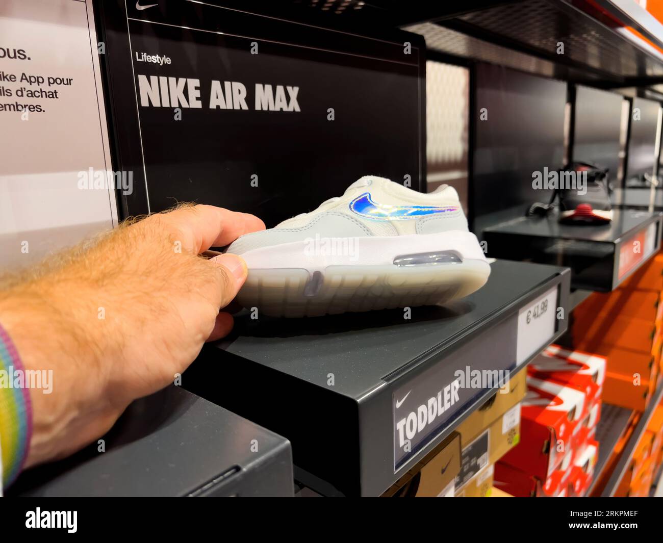 Roppenheim, Francia - 11 luglio 2023: Scarpe sportive POV maschili che  tengono in mano il nuovo bambino Nike Air Max al prezzo di 41,99 euro nel  negozio outlet - bianche con Swoosh blu Foto stock - Alamy