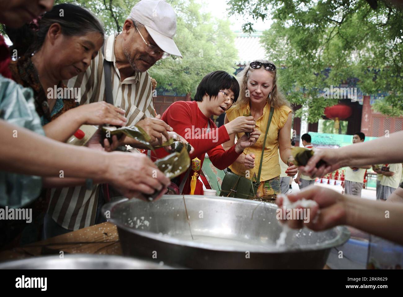 Bildnummer: 58131687 Datum: 21.06.2012 Copyright: imago/Xinhua (120621) -- PECHINO, 21 giugno 2012 (Xinhua) -- un visitatore straniero impara a fare Zongzi, un gnocco a forma di piramide fatto di riso glutinoso avvolto in foglie di bambù o canne, al Museo delle arti popolari di Pechino per celebrare l'upcomimg Dragon Boat Festival a Pechino, capitale della Cina, il 21 giugno 2012. Durante l'avvicinarsi del festival si terranno varie attività, tra cui la realizzazione di Zongzi, la barca da corsa con drago e il bere vino realgar. Il Dragon Boat Festival, chiamato anche Duanwu Festival, è tradizionalmente celebrato il quinto giorno del quinto l Foto Stock