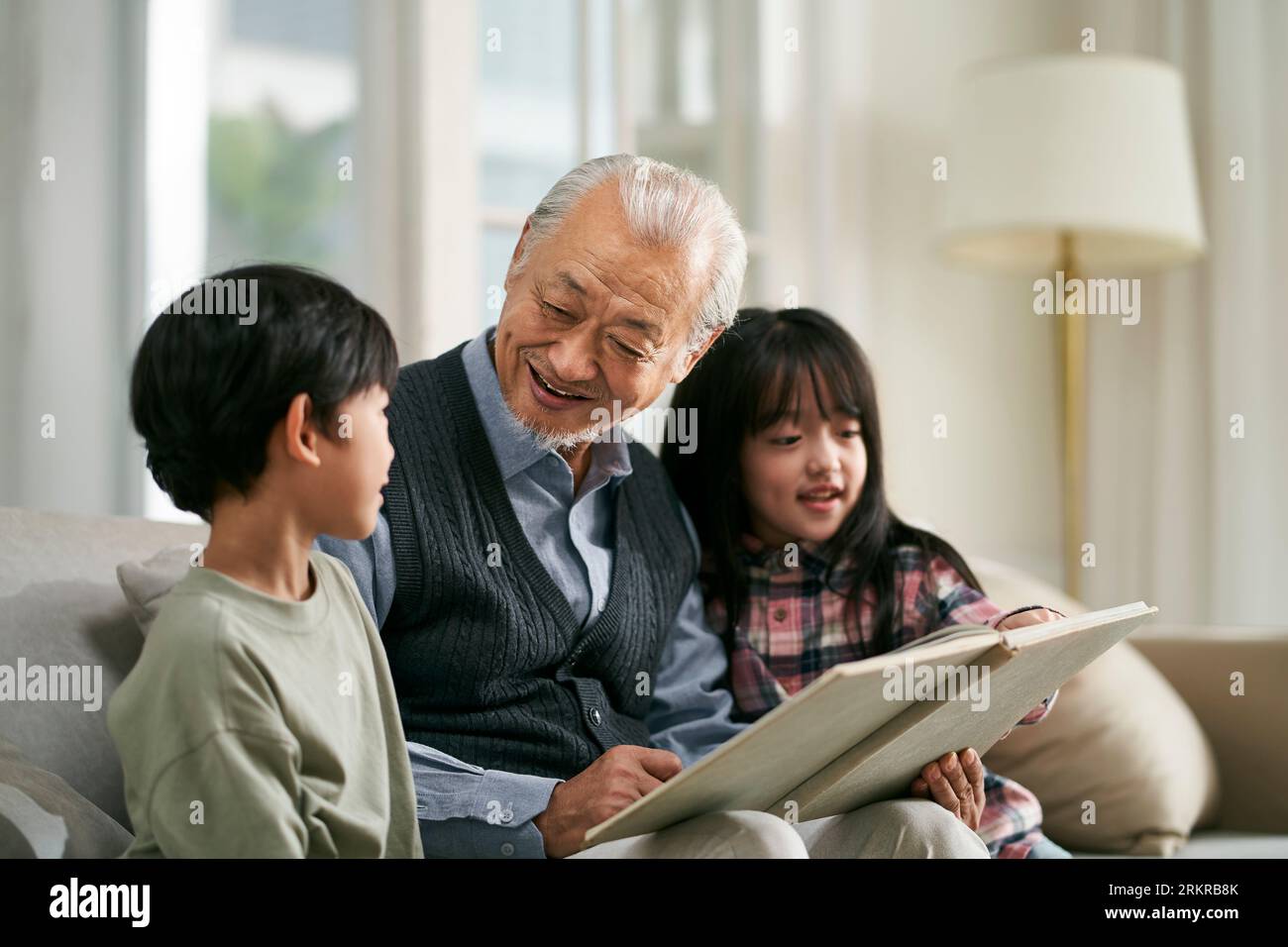 nonno asiatico anziano che si diverte con due nipoti a casa Foto Stock