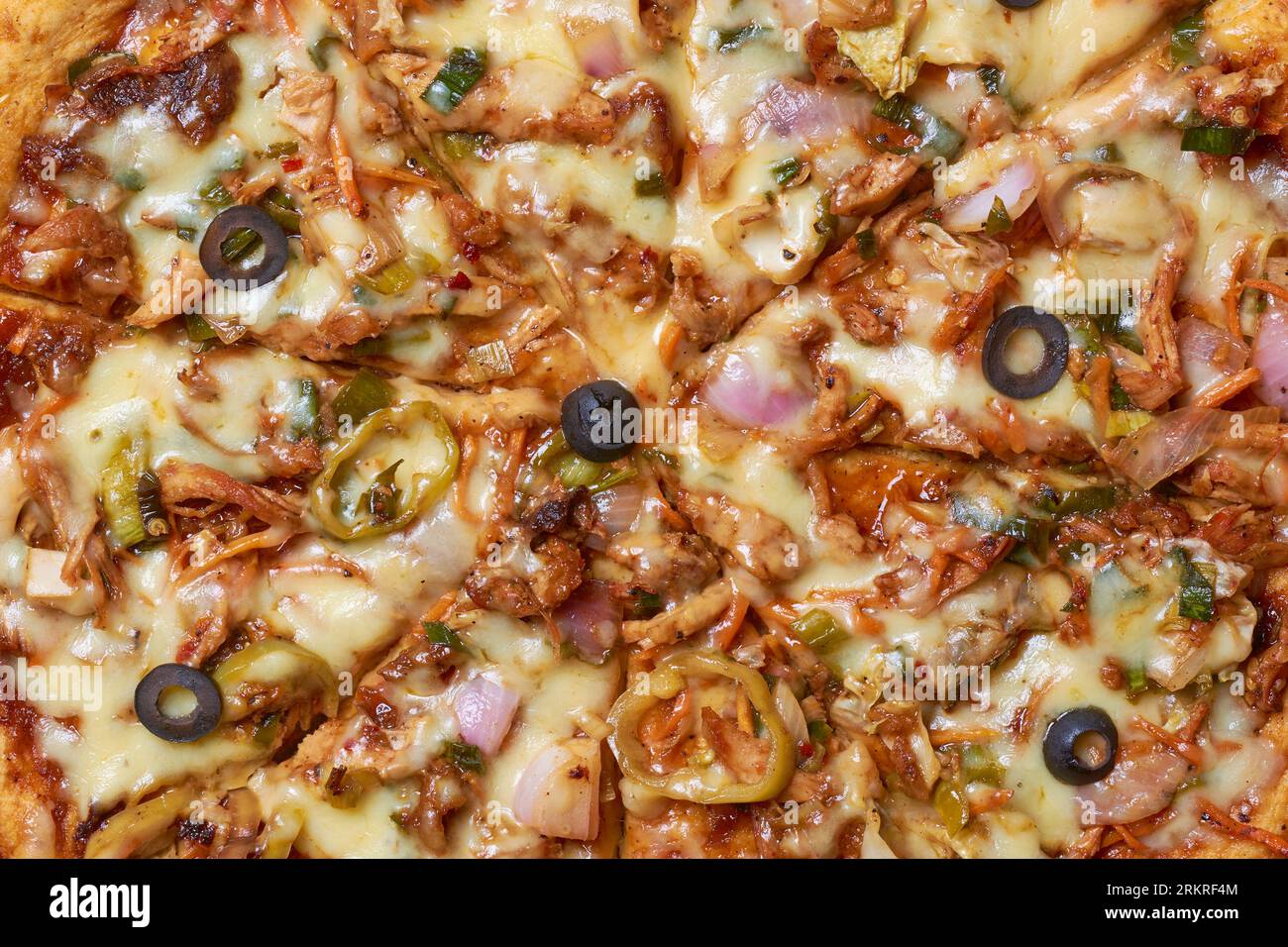 primo piano della pizza di pollo speziata e diabolica, della pizza appena preparata mescolata con verdure alla griglia, olive e doppi strati di mozzarella, strai Foto Stock