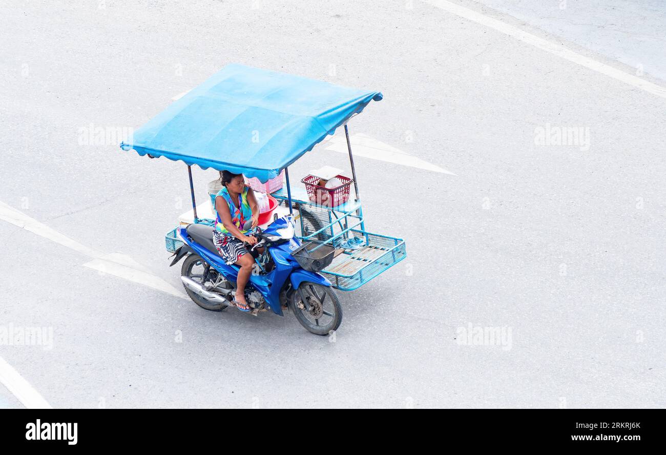 Donna che guida una moto leggera con sidecar e tettoia a Pattaya, Thailandia. Questi sidecar sono comuni in Thailandia e particolarmente popolari tra st Foto Stock