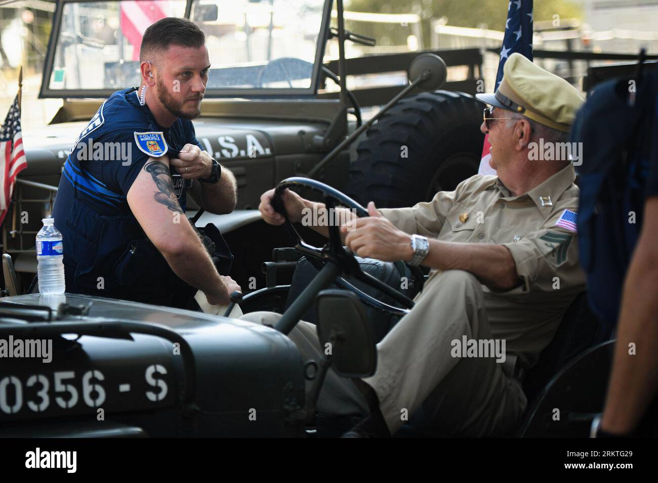 Avignone, Francia. 25 agosto 2023. Un ufficiale di polizia municipale francese mostra un tatuaggio a un ufficiale di fanteria degli Stati Uniti. In occasione del 79° anniversario della liberazione di Avignone in Francia durante la seconda guerra mondiale, di fronte al municipio si svolge una mostra che mostra una serie di veicoli militari e civili. Credito: SOPA Images Limited/Alamy Live News Foto Stock