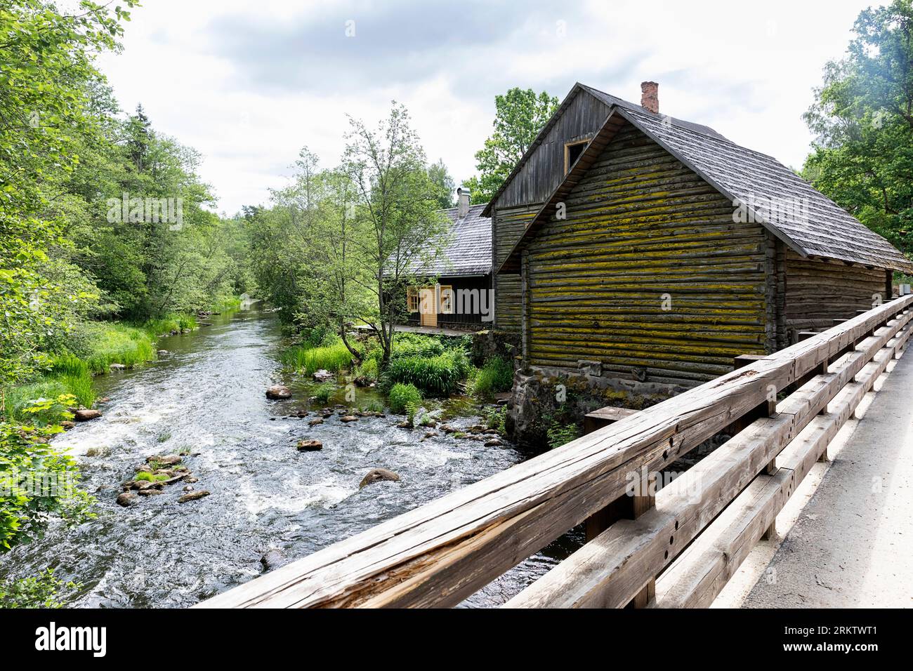 Un ponte che attraversa il bellissimo fiume Vohandu nella zona di Suvahavva, con case in legno tradizionali abbandonate sulla riva del fiume, Estonia Foto Stock