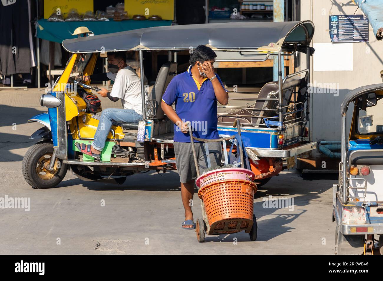 SAMUT PRAKAN, THAILANDIA, FEB 02 2023, Un portatore spinge un carrello con i cesti per trasportare un acquisto dal mercato Foto Stock