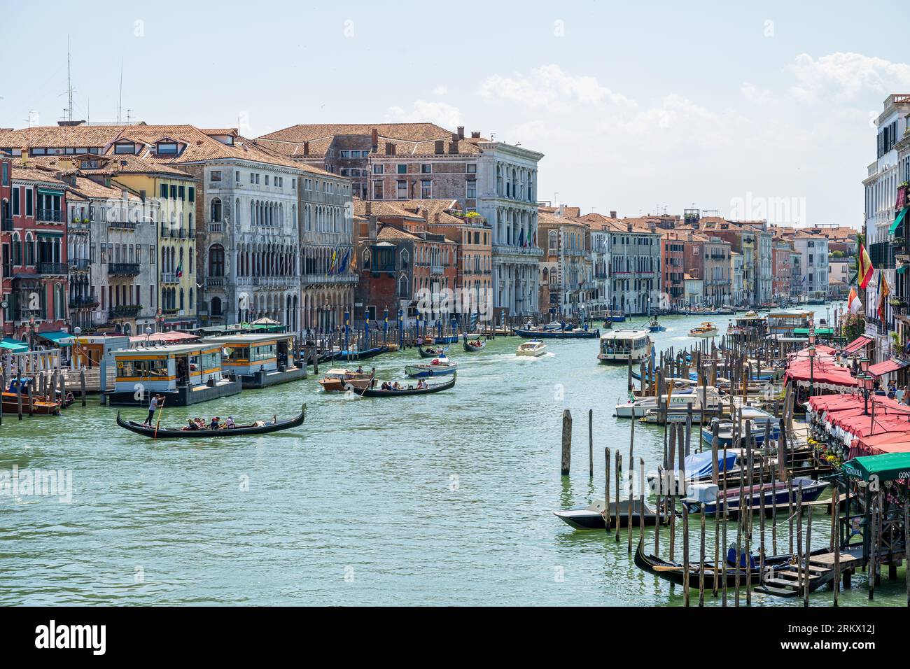 Vista di un giorno d'estate dal Ponte di Rialto, Venezia, Italia lungo il canale navigabile con molte gondole e altre barche. Foto Stock
