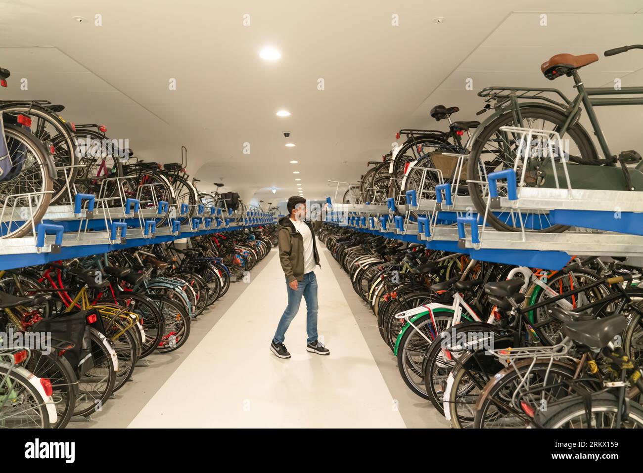 Amsterdam, Paesi Bassi - 17 luglio 2023: L'uomo lascia la sua bici al parcheggio sotterraneo per biciclette multipiano presso la stazione centrale. Foto Stock